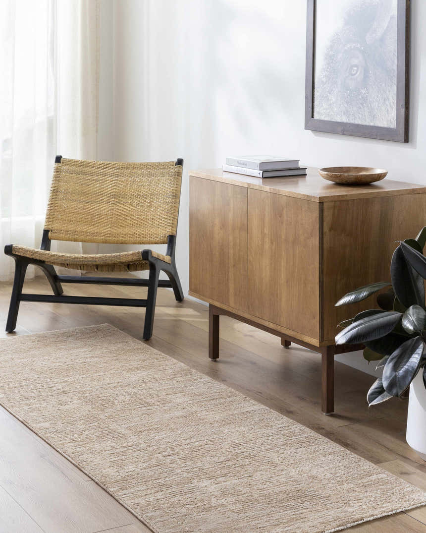 Living room scene with a Kahua Tan Area Rug, woven chair, and wood cabinet with decor. Roomscene-Runner