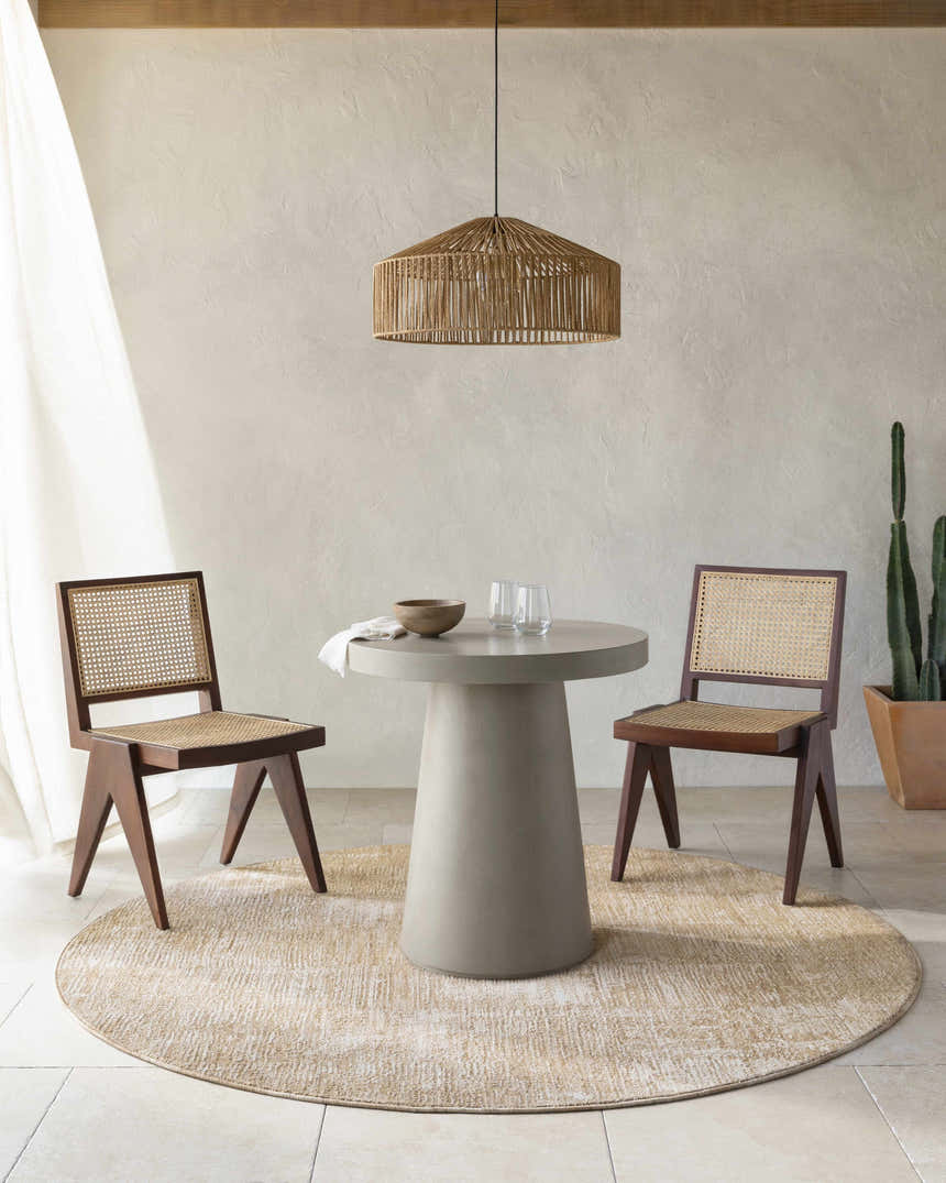 Neutral dining room with a round Kahua Tan Area Rug under a concrete table and wood chairs. Roomscene-Round