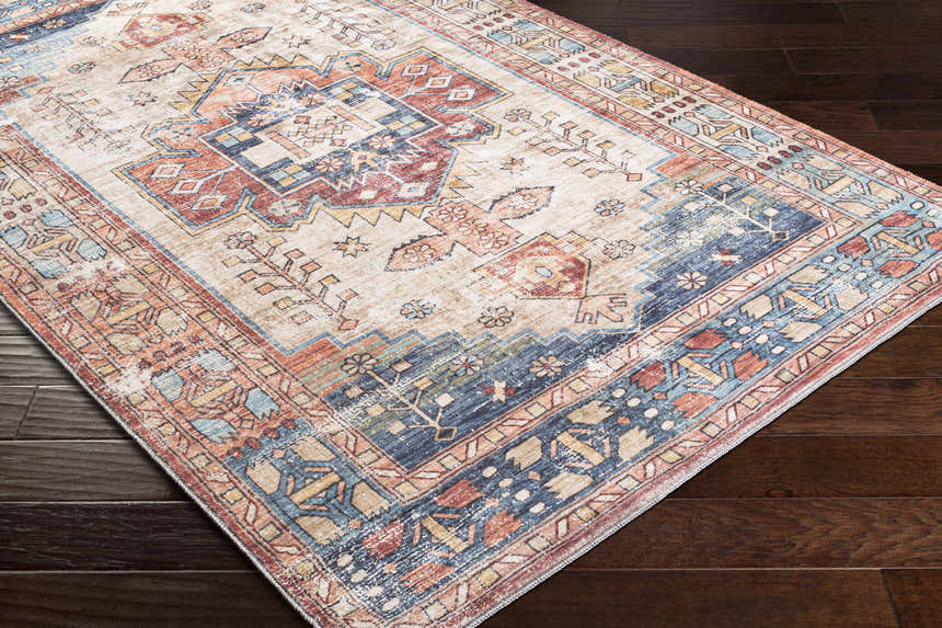 Close-up of the Snell Area Rug. Traditional Southwestern design in amber, brick red, coral, and blue tones. Corner