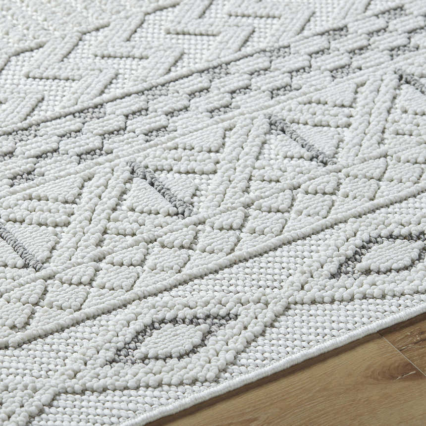 Close-up of the Sokka Area Rug, a cream and light gray rug with a textured, geometric pattern. Texture
