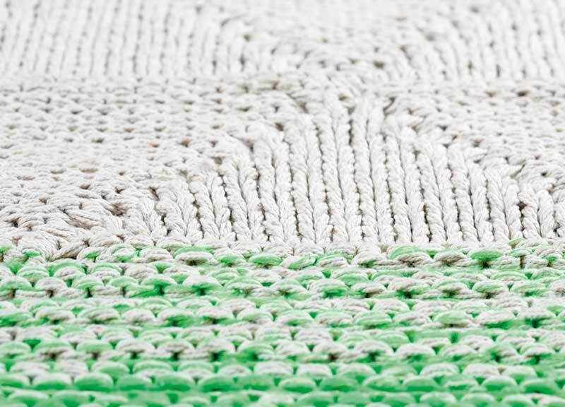 Close-up of hand-woven Snyder Area Carpet rug, showing green and off-white textures and patterns. Styleshot