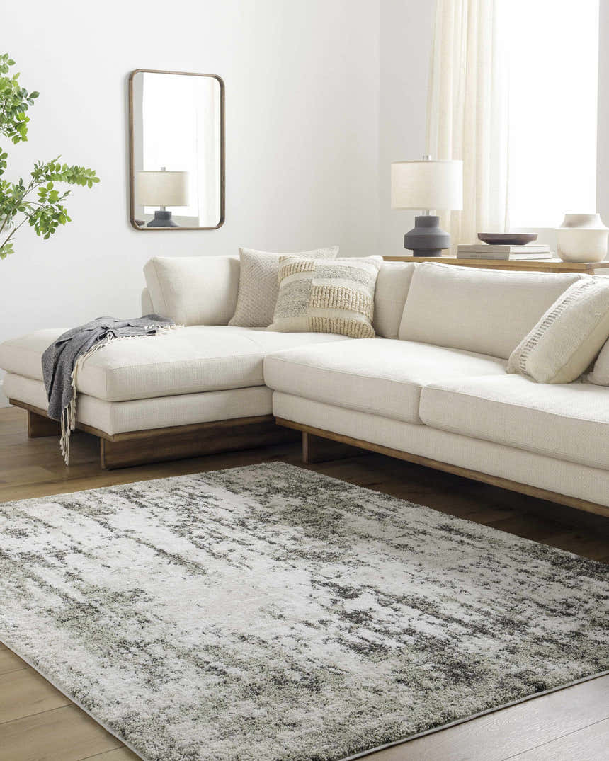 Living room with a light gray Omari Area Rug, cream sectional sofa, wood floors, and neutral decor. Roomscene-Rectangle