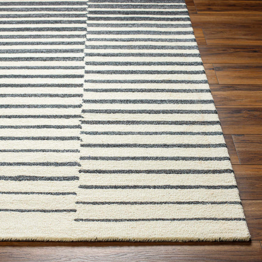 Close-up of the Gawel Charcoal Area Rug featuring a striped pattern in charcoal, beige, and wool texture on wood floors. Front
