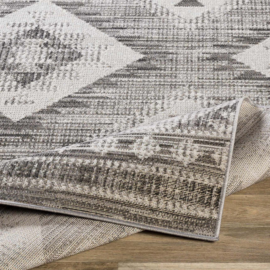 Close-up of the Spade Area Rug featuring geometric black, gray, and white pattern with a machine woven texture. Fold