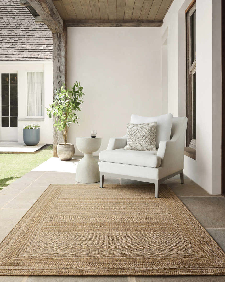 Covered patio with a beige Freja Flatweave Faux Jute Rug, white chair, and stone side table. Roomscene-Rectangle