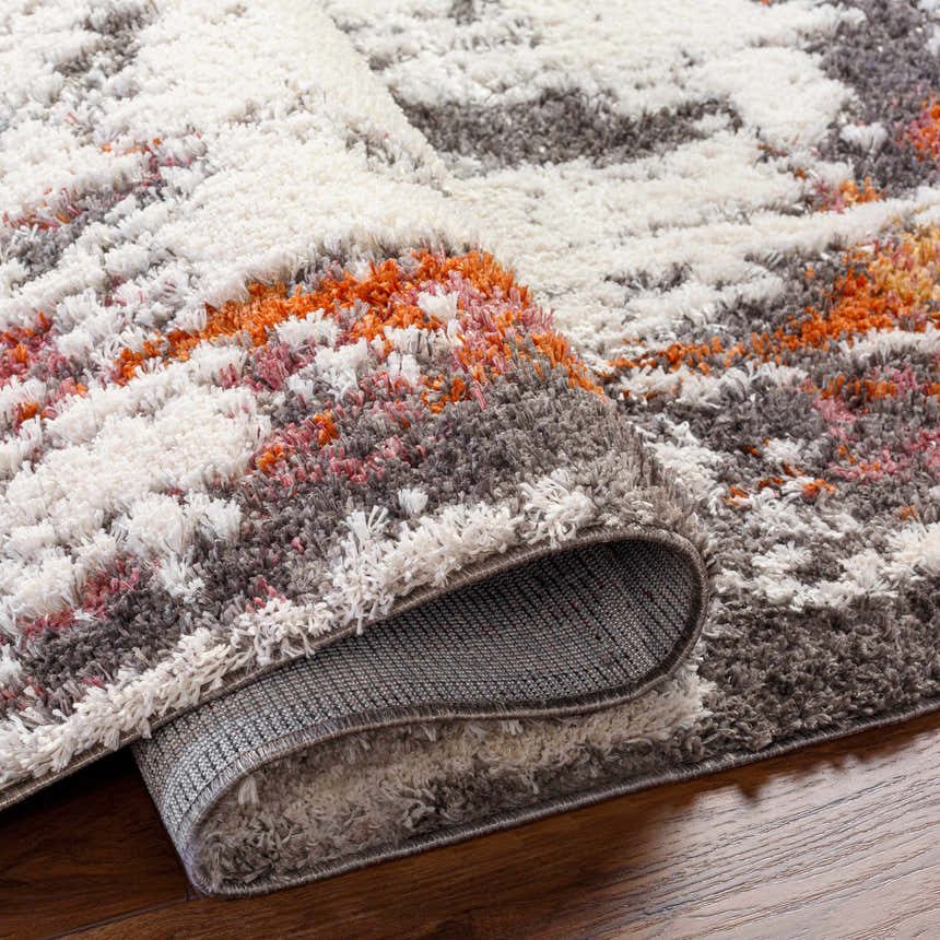 Close-up of the shaggy Shep Area Rug, featuring dark beige, brown, lambswool, and smoke colors. Contemporary style. Fold