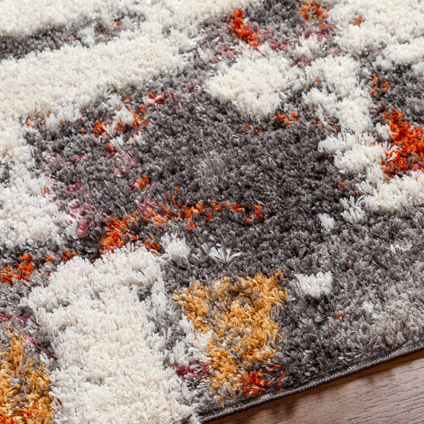 Close up of the Shep Area Rug, a shag rug in dark beige, dark brown, lambswool, and smoke colors. Texture