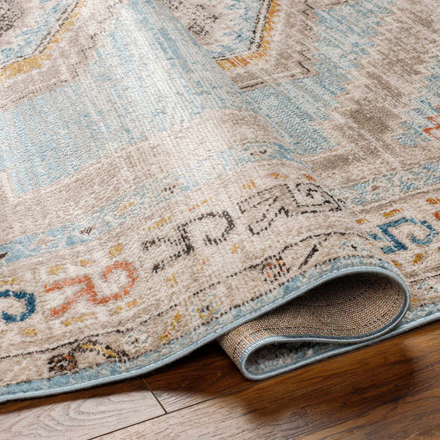 Close-up of the Iresh Area Rug showing its cloud gray, beige, and blue traditional pattern and soft polypropylene texture. Fold