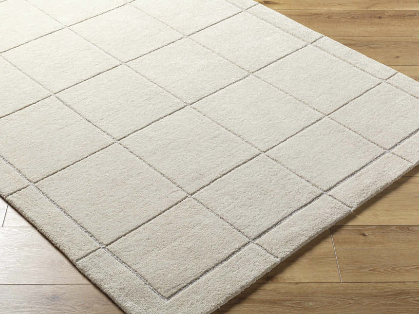 Close-up of the Siarl Cream Checkered Area Rug, a beige wool rug with a contemporary square pattern on wood flooring. Corner