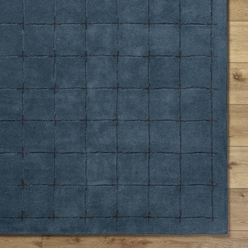 Close-up of the Sanvi Navy Wool Area Rug. Hand-tufted wool rug with a contemporary grid pattern in navy and black. Corner