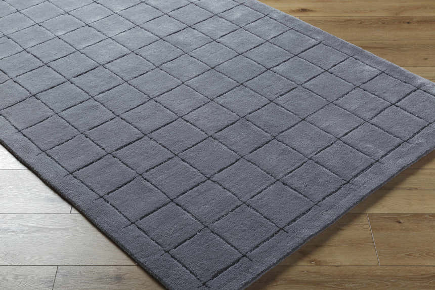 Close-up of the Sanvi Charcoal Area Rug. Hand-tufted wool rug with a contemporary square pattern in shades of black and charcoal. Corner