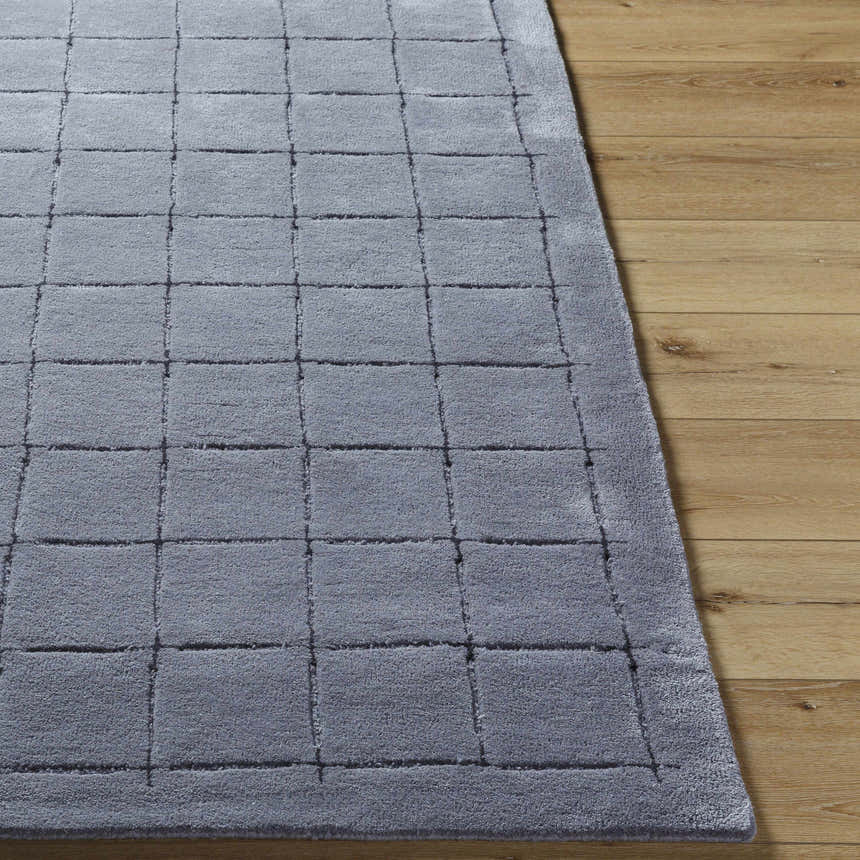 Close-up of the hand-tufted Sanvi Charcoal Area Rug. The 100% wool rug has a contemporary grid pattern and soft texture. Front