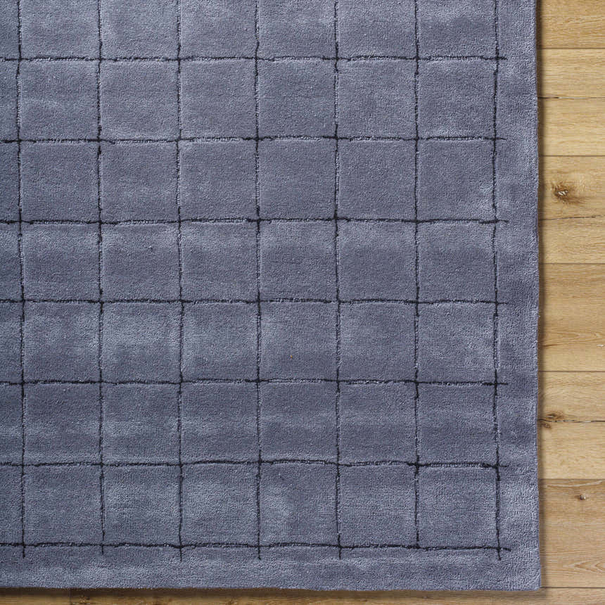 Close-up of the Sanvi Charcoal Area Rug. Hand-tufted wool rug with a contemporary grid pattern in black and charcoal. Corner