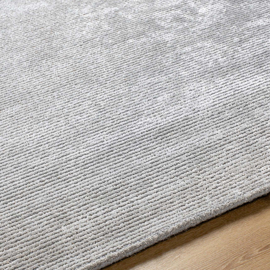 Close up of the hand-tufted Noham Area Rug in metallic silver and pale slate, showing texture and pattern. Texture