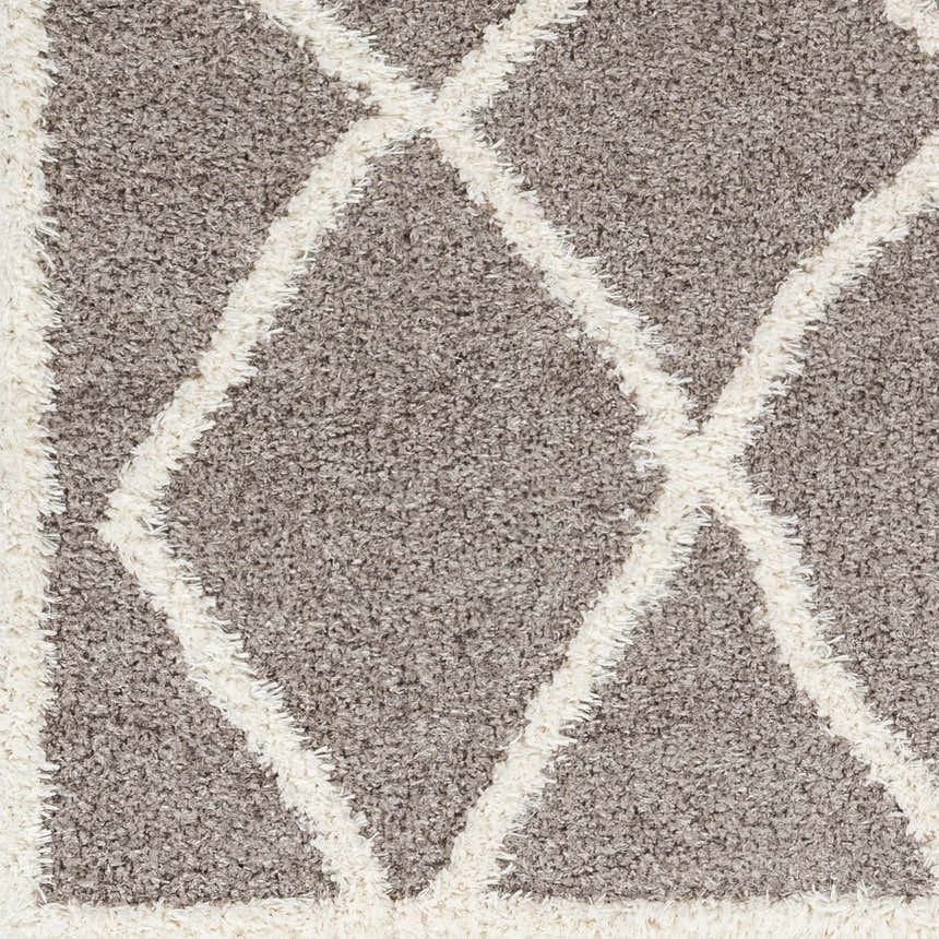 Close-up of the Alkas Area Rug. Dark gray shag rug with a geometric, off-white diamond pattern. Soft, textured polyester. Swatch