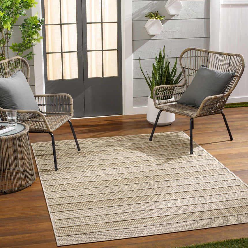 Outdoor patio scene with the beige striped Idana Area Rug, wicker chairs, and wood flooring. Roomscene-Rectangle