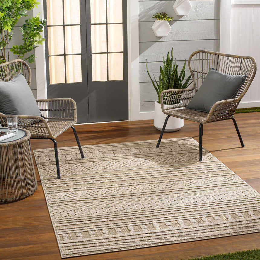 Outdoor patio scene with wicker chairs and a Kojo Lambswool Area Rug in a camel and beige geometric pattern. Roomscene-Rectangle