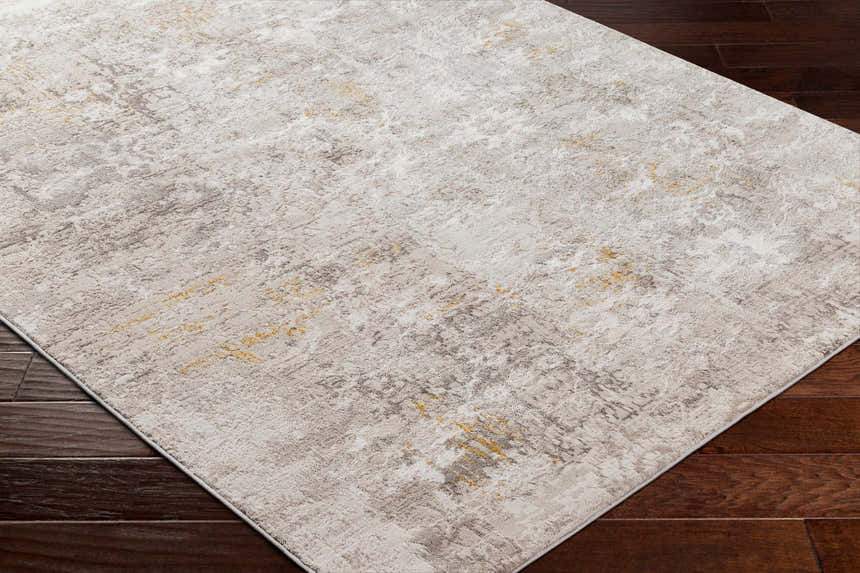 Close-up of the Yuji Area Rug in Beachhouse, showing its abstract pattern and neutral tones on dark wood floors. Corner