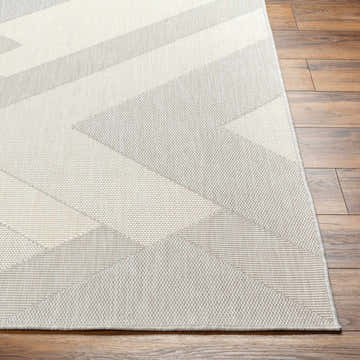 Close-up of the Adwen Cream Area Rug showing its beige and gray geometric pattern and woven texture on wood floor. Front