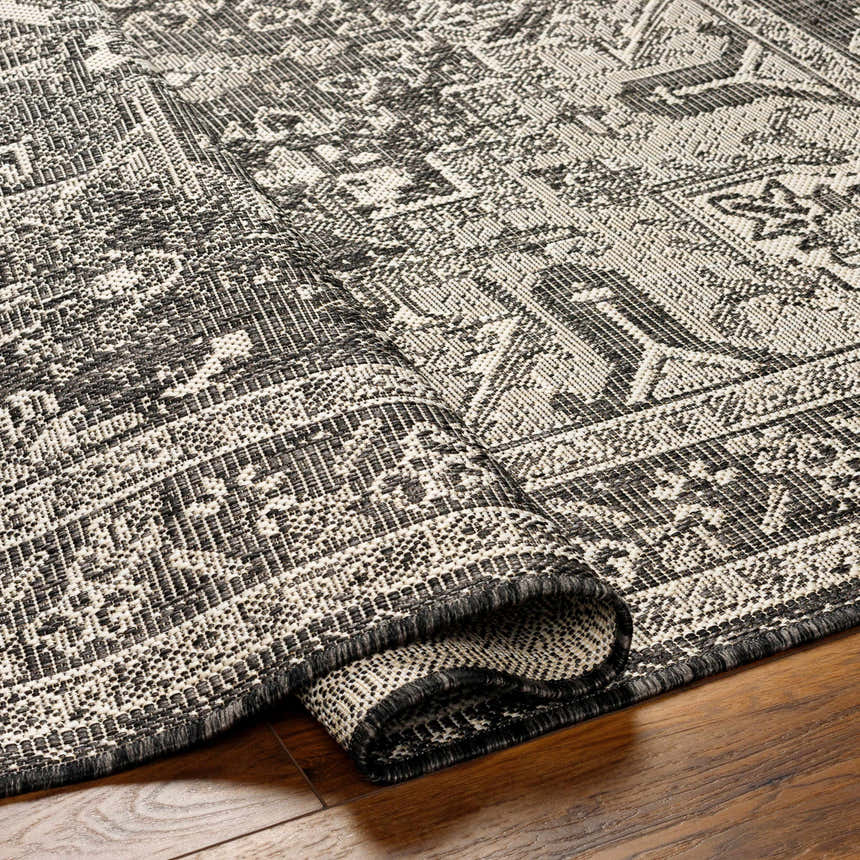 Close-up of the Cohen Nutmeg Area Rug showing its beige, bone, and charcoal traditional pattern and woven texture. Fold