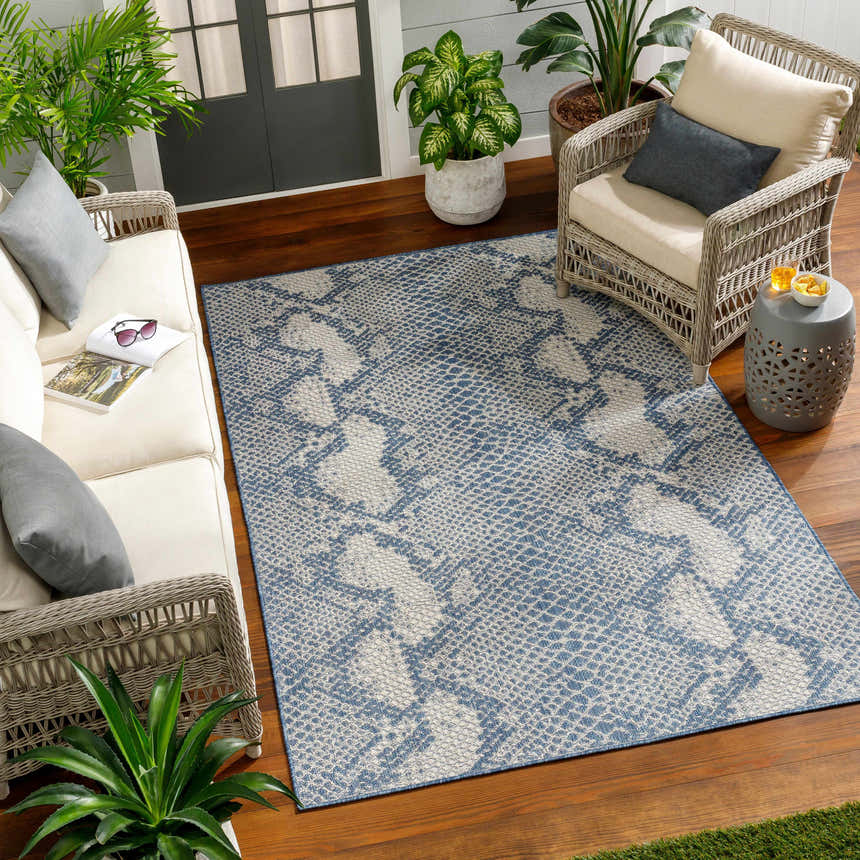 Cozy sunroom with Estee Blue Snake-Patterned Area Rug, wicker furniture, and potted plants on a wood floor. Roomscene-Rectangle