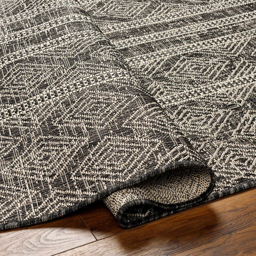 Close-up of Gavin Nutmeg area rug showing diamond pattern in beige, bone, and gray on hardwood floor. Transitional style. Fold