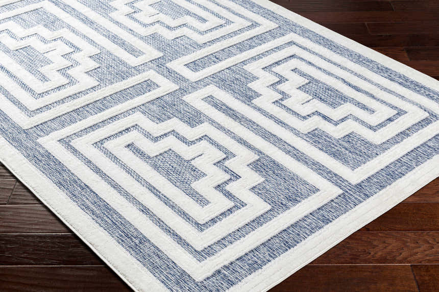 Close-up of the Yves Blue Outdoor Rug, a contemporary rectangle rug with a white geometric pattern on a blue background. Corner