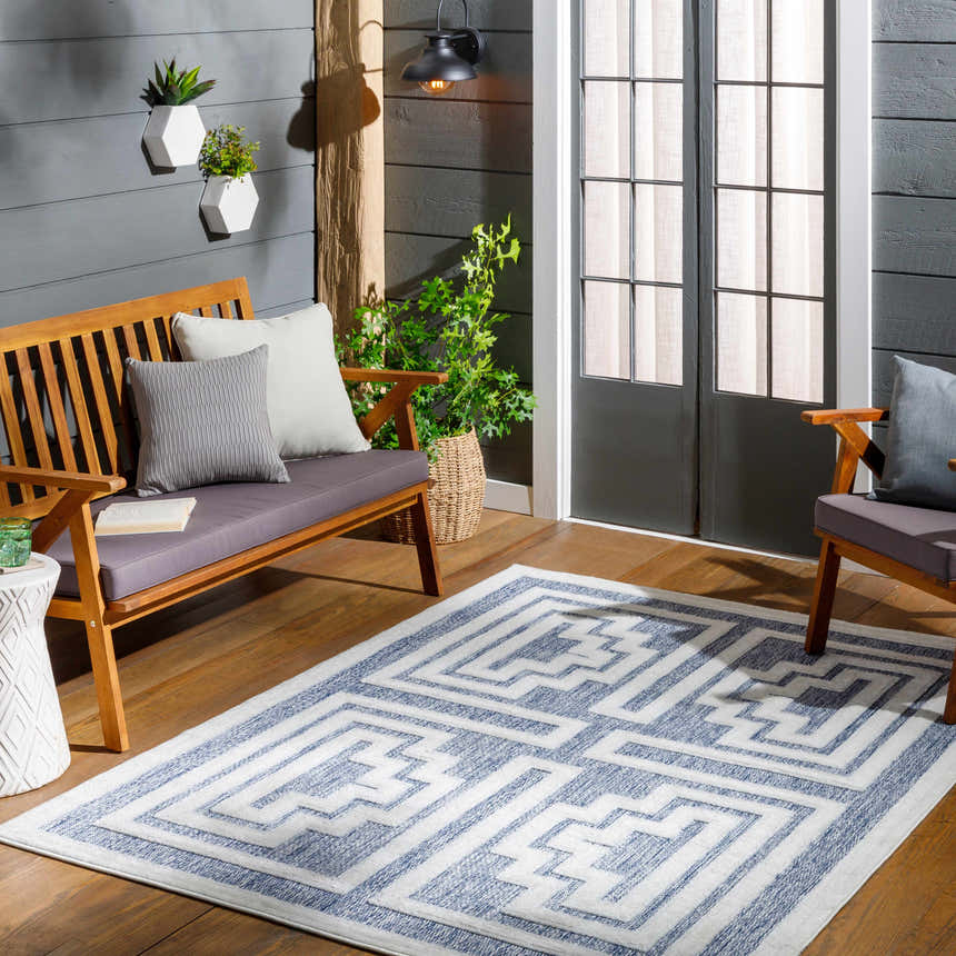 Outdoor patio scene with wood furniture and Yves Blue Outdoor Rug featuring a geometric pattern. Roomscene-Rectangle