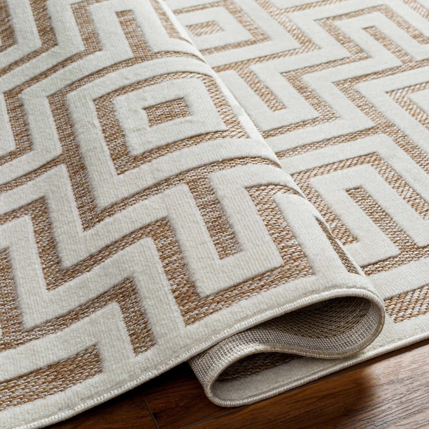 Close-up of the Zevi Tan Outdoor Rug showing its geometric pattern, tan and cream colors, and textured weave. Fold