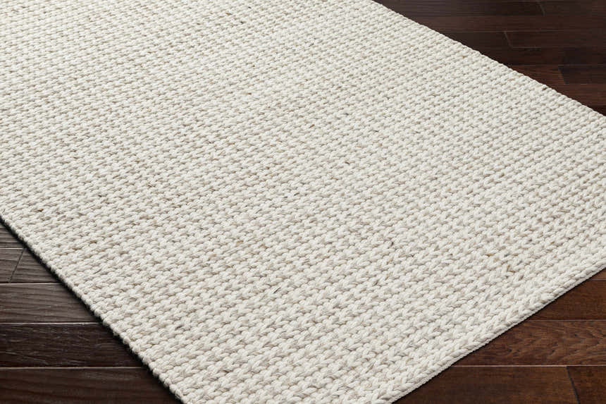 Close-up of the hand-woven Lenci Antique Beige Area Rug. Beige and bone tones with a textured, contemporary design. Corner