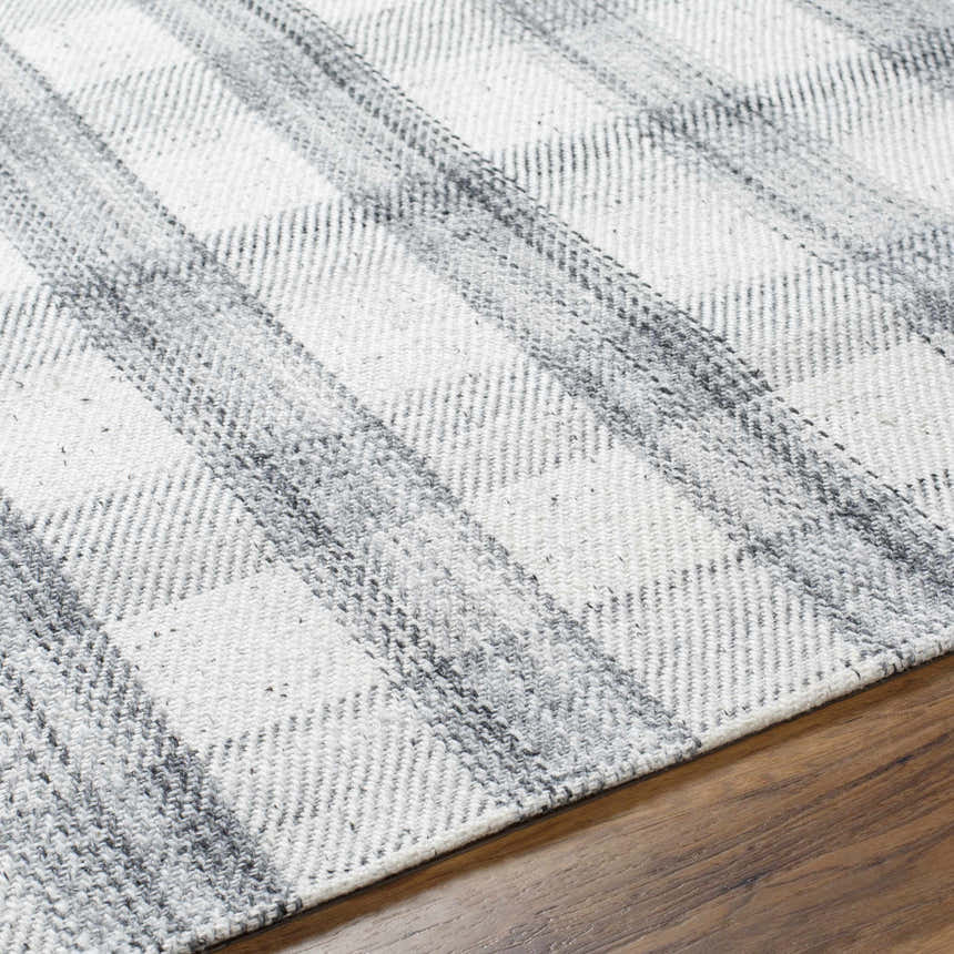 Close up of the Leeba Gray Plaid Area Rug showing the woven texture and gray and white pattern on a wood floor. Texture