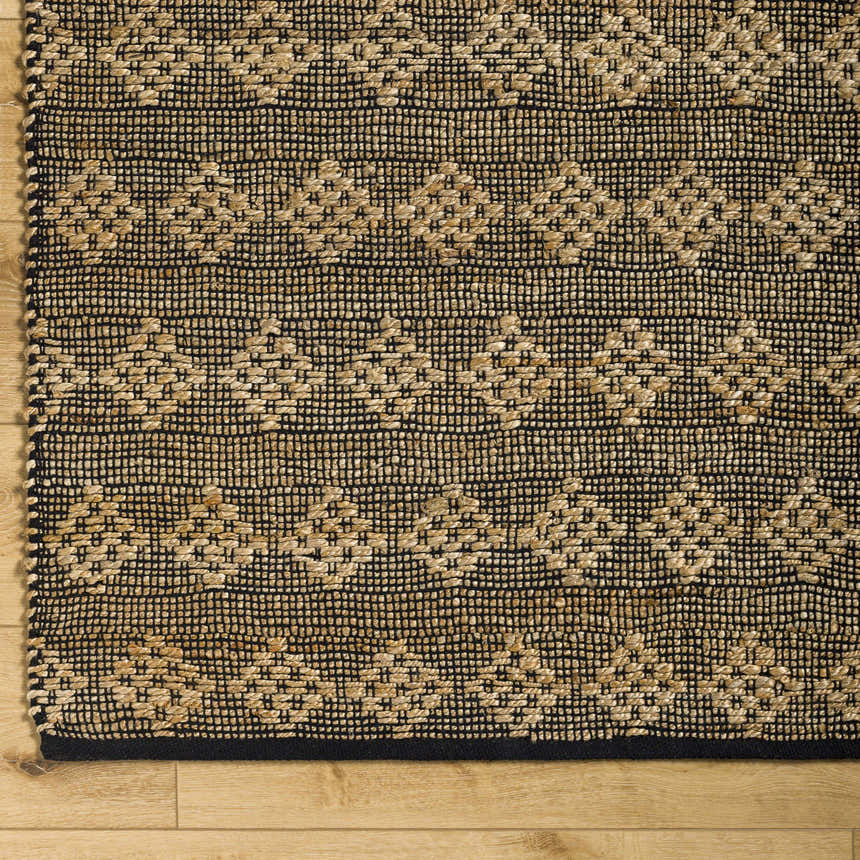 Close-up of the hand woven Irina Area Rug. Medium brown and nutmeg jute and cotton rug with geometric pattern. Corner