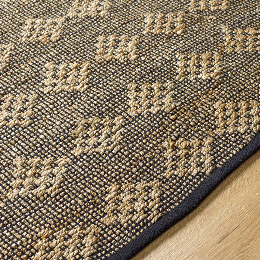 Close-up of the hand-woven Irina Area Rug. The jute and cotton rug has a geometric pattern in medium brown and nutmeg. Texture