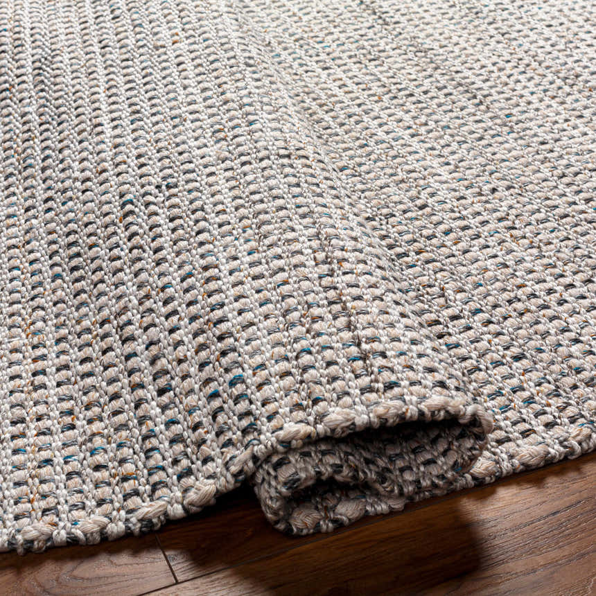 Close-up of the hand woven Beige Teal Aron Area Rug showing texture and pattern detail on a wood floor. Fold