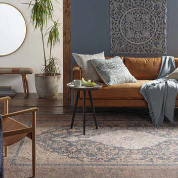 Living room scene with a brown leather sofa and Staplehurst Washable Area Rug in beige, brick red, and dark blue. Roomscene-Rectangle