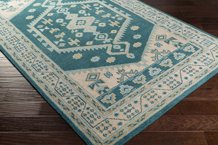 Close-up of the hand-knotted Stepps Area Rug. Aqua, beige, and sage colors in a traditional, bohemian pattern. 100% wool. Corner