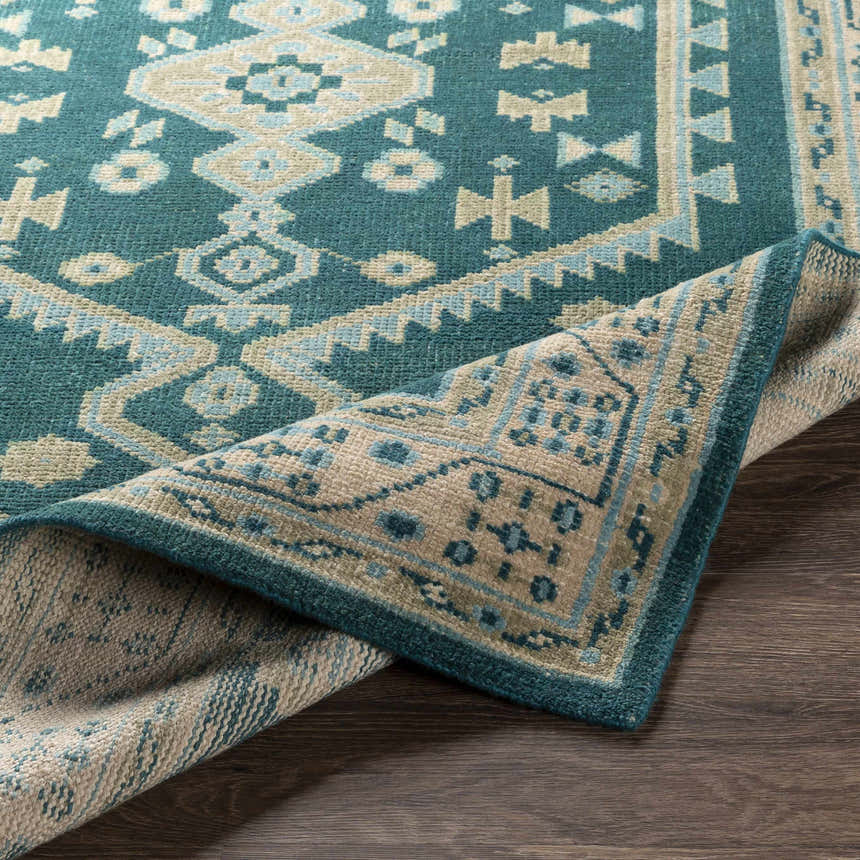 Close-up of the hand-knotted Stepps Area Rug, showcasing its aqua, beige, and teal bohemian design and wool texture. Fold