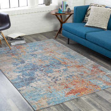 Living room scene with a blue sofa and Stallingborough Area Rug in blue, rust, and cream. Roomscene-Rectangle