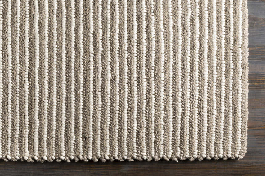 Close-up of the hand woven Sula Area Rug. Cream and gray wool rug with a striped pattern and textured design. Corner