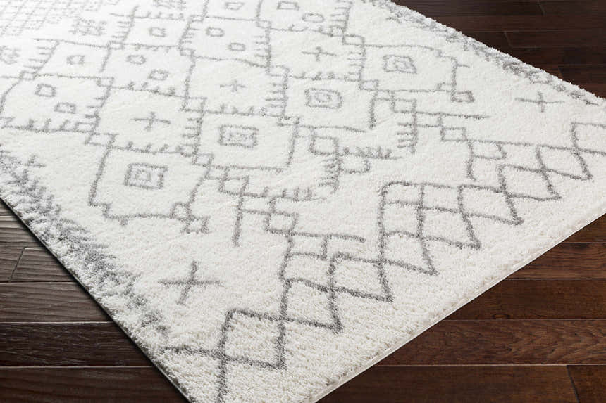 Close up of the Sutterton Area Rug. Cream rug with gray geometric pattern. Corner
