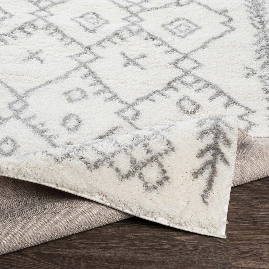 Close-up of the Sutterton Area Rug. Cream rug with a gray geometric pattern and soft, plush texture. Fold