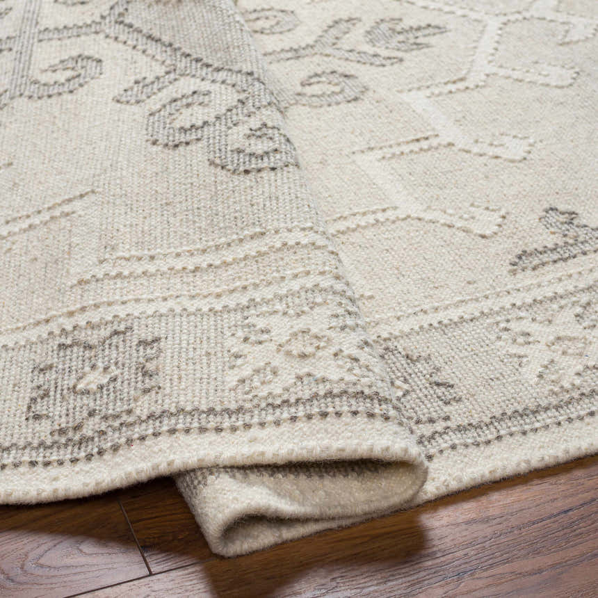 Close-up of the hand woven Afra Area Rug. Gray farmhouse style wool rug with traditional pattern and texture. Fold