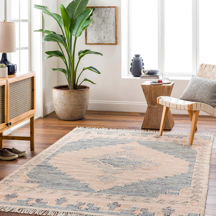 Living room scene with a light brown Lana Area Rug, wood furniture, and a large potted plant. Roomscene-Rectangle