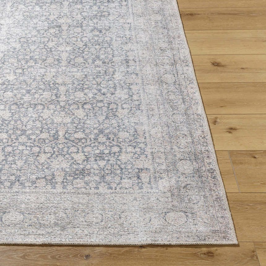 Close-up of the Odele Washable Area Rug in medium gray with a traditional pattern on light wood flooring. Front