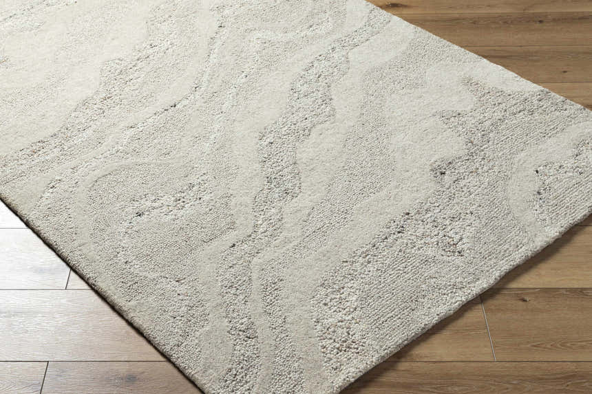 Close up of the Siani Cream Wool Area Rug showing its ash and silver gray tones and hand-tufted texture. Corner