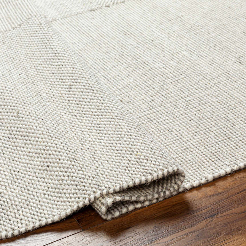 Close-up of the hand woven Abhay Beige Wool Area Rug showing texture and detail on hardwood floor. Fold