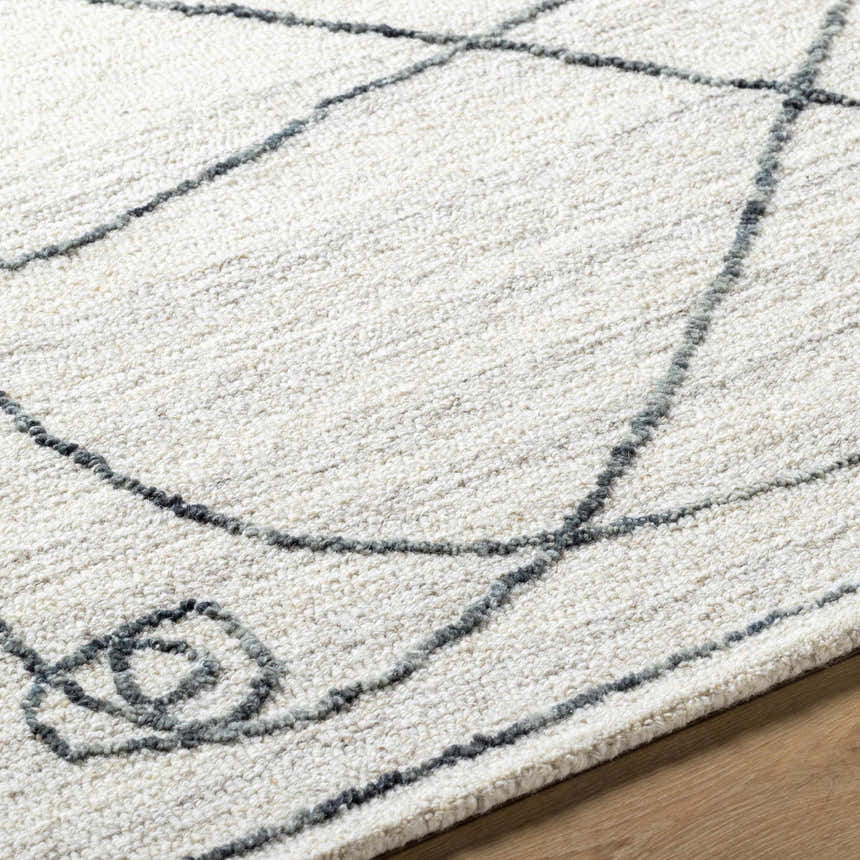 Close-up of the Sabah Area Rug showing its off-white base and light silver geometric line pattern and hand-tufted texture. Texture