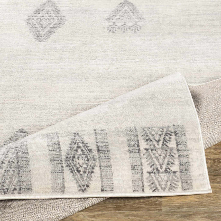 Close-up of Wakita Light Gray Tribal Rug showing its gray geometric pattern and texture. Machine woven polypropylene rug. Fold