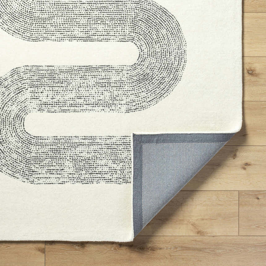 Close-up of the Saura Wool Area Rug showing its ivory color and charcoal dotted, curved line design. Fold