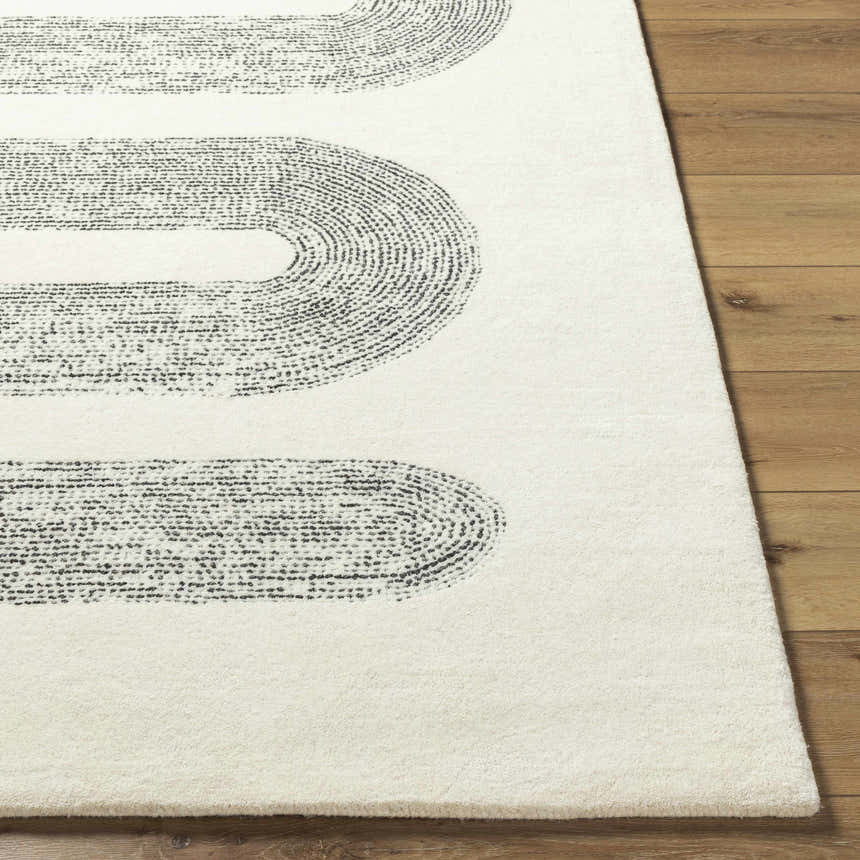 Close up of the Saura Wool Area Rug showing the charcoal oval pattern on ivory wool with wood floors. Front